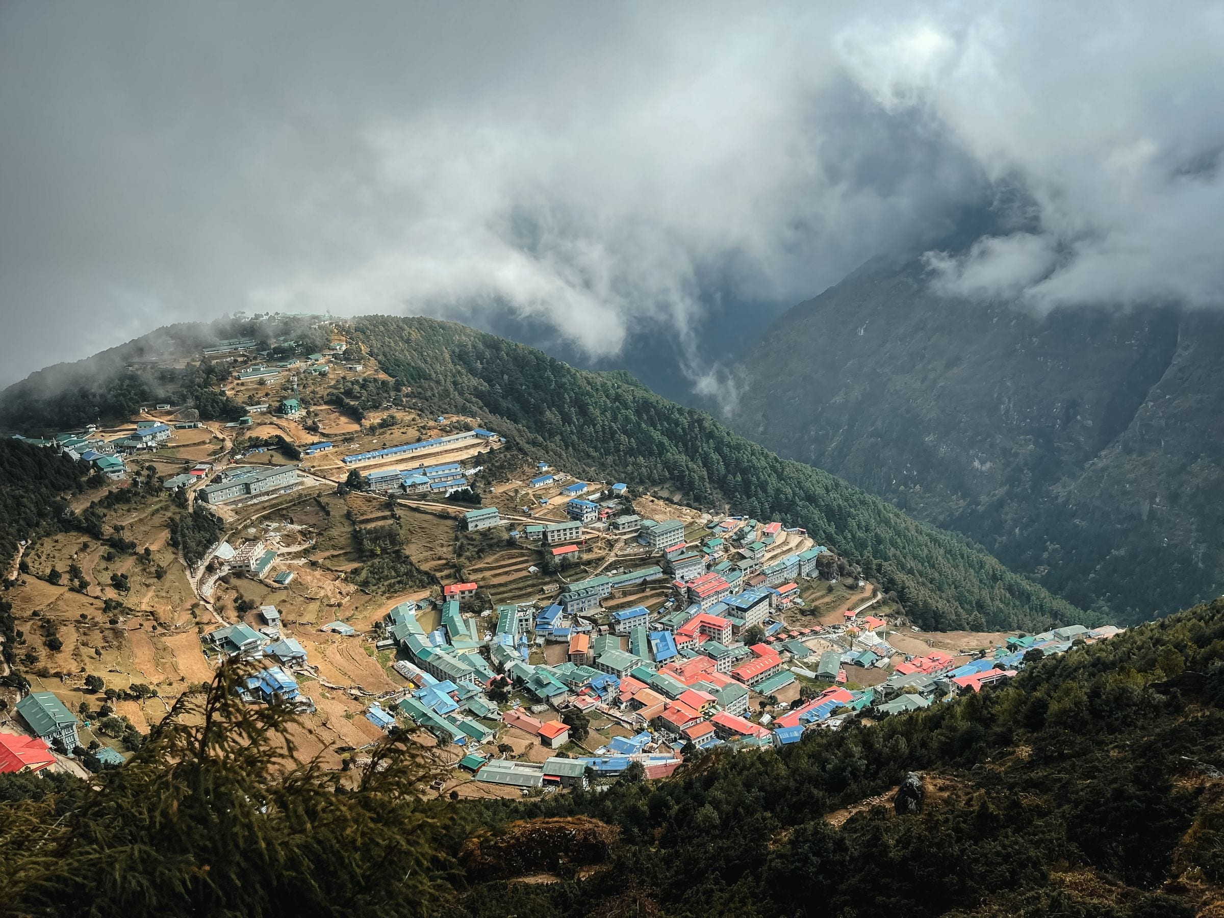Namche Bazaar seen from above, its painted roofs stacked in a mountain amphitheatre