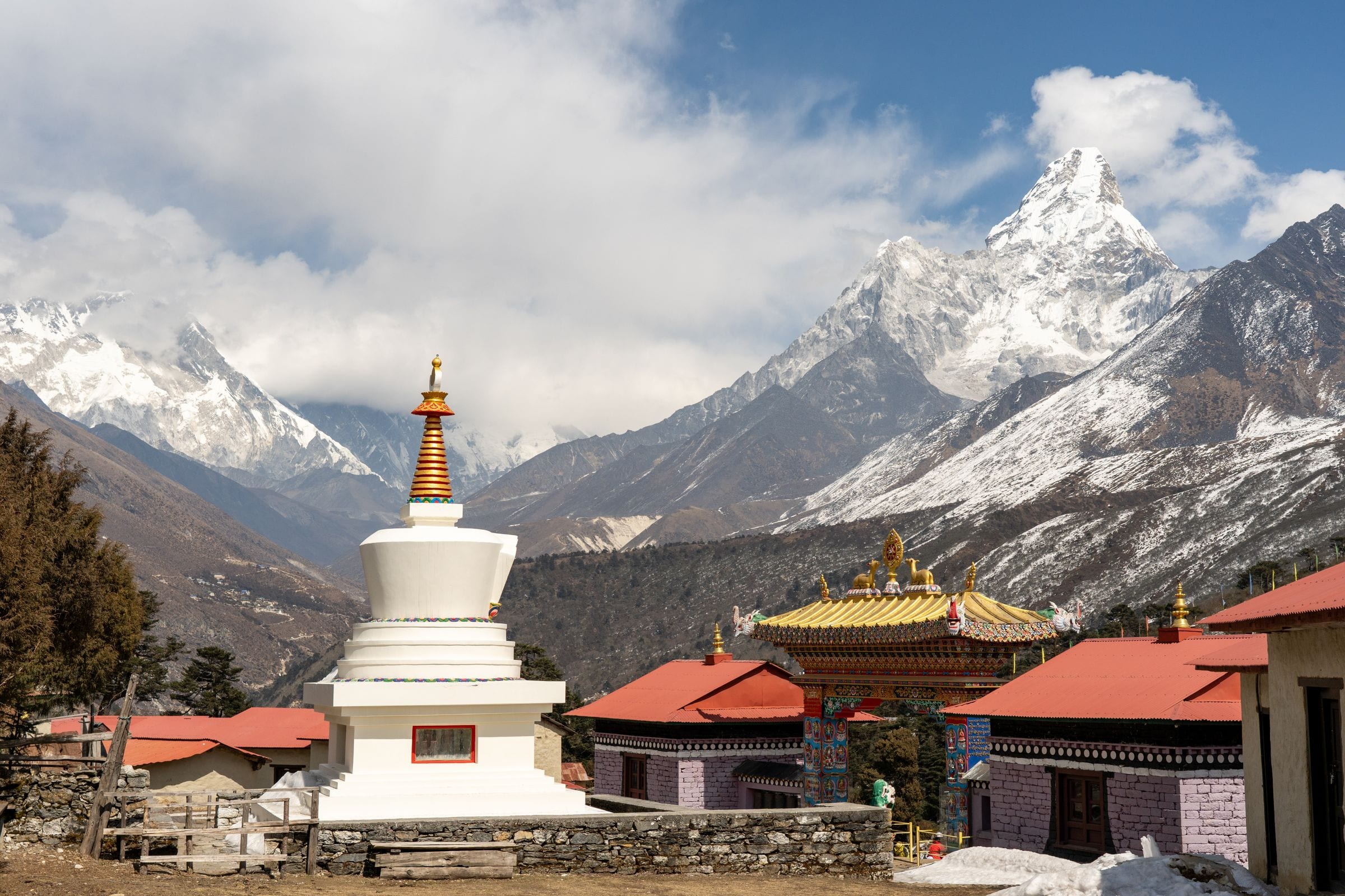 A white stupa and monastery roofs below Ama Dablam in the Everest region