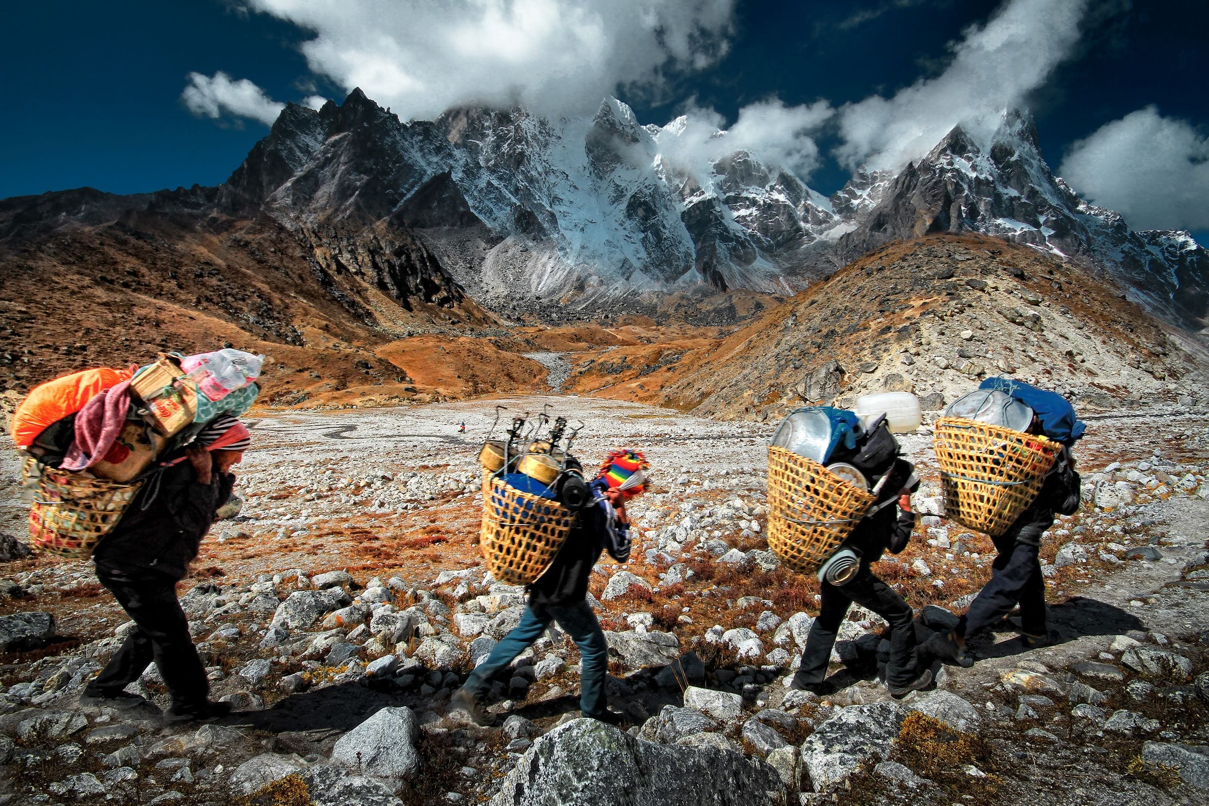 Porters carrying loads along a high Himalayan moraine trail