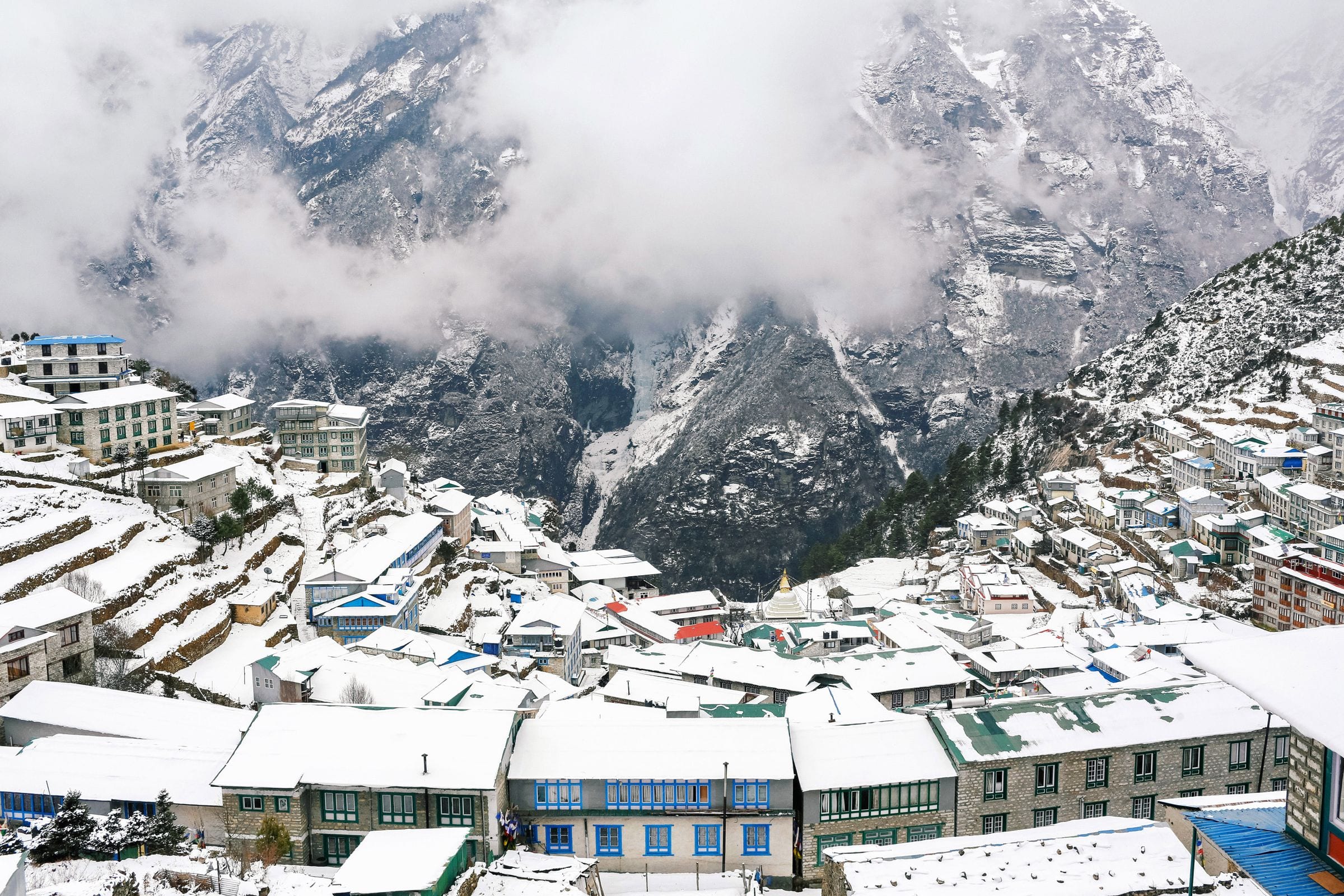 Namche Bazaar under fresh snow beneath cloud-covered peaks