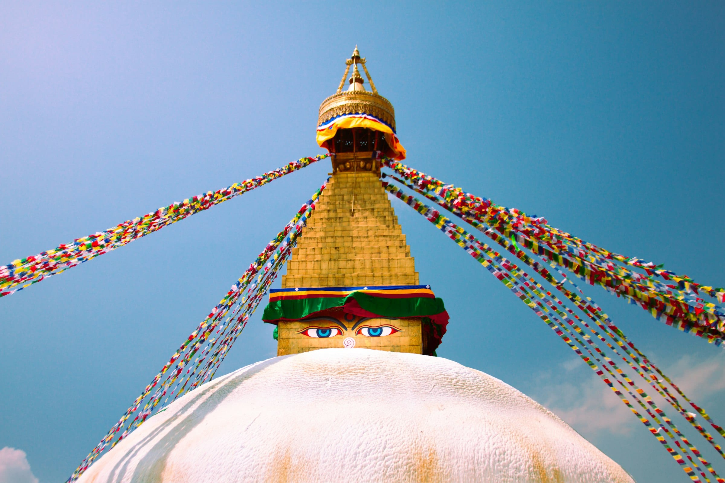 The painted eyes of Boudhanath stupa in Kathmandu beneath strings of prayer flags