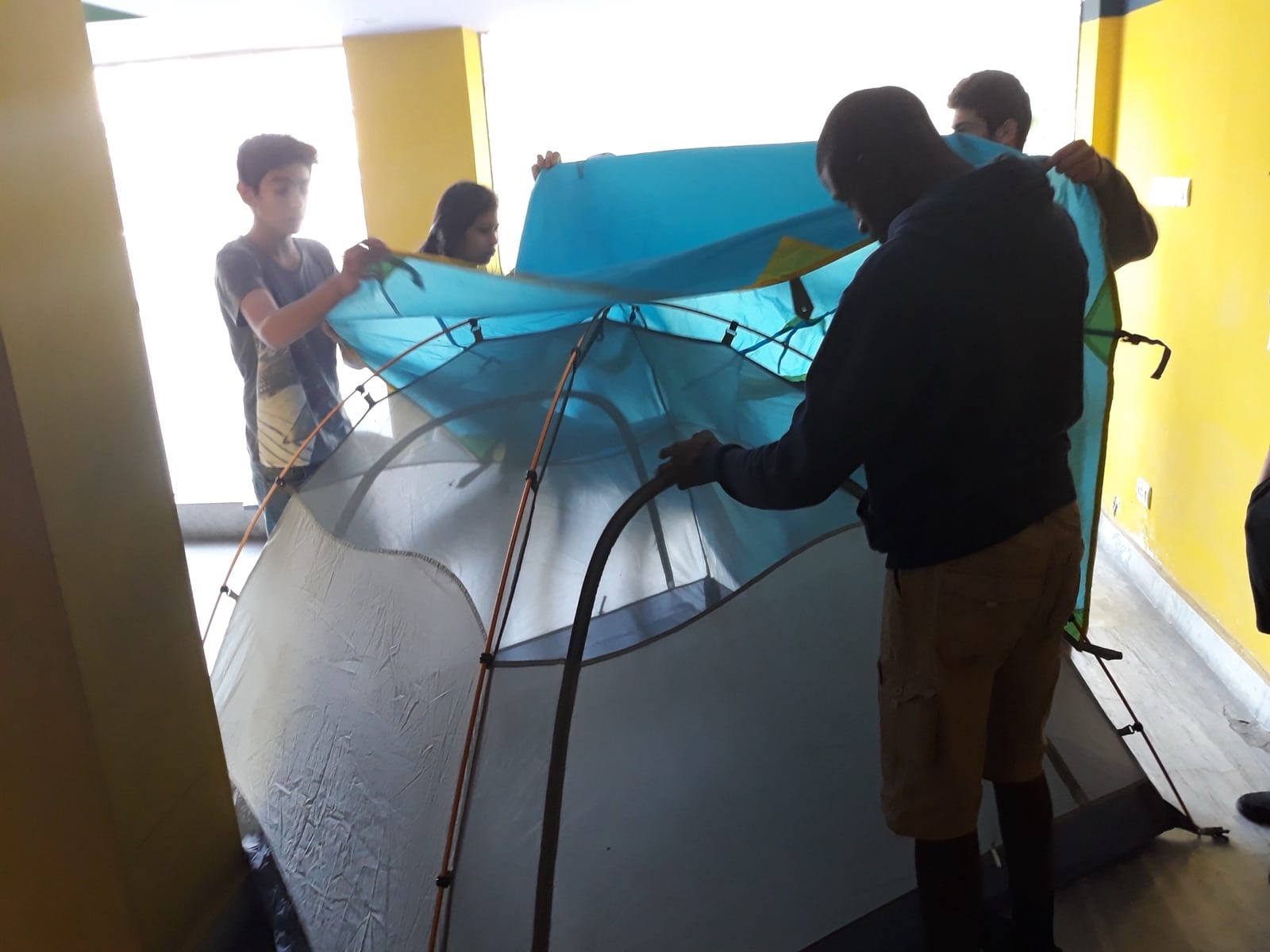 Students practising pitching a dome tent indoors on the preparation day