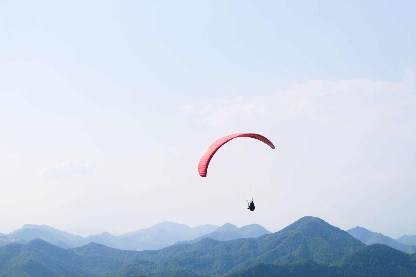 Paraglider soaring above a mountain range