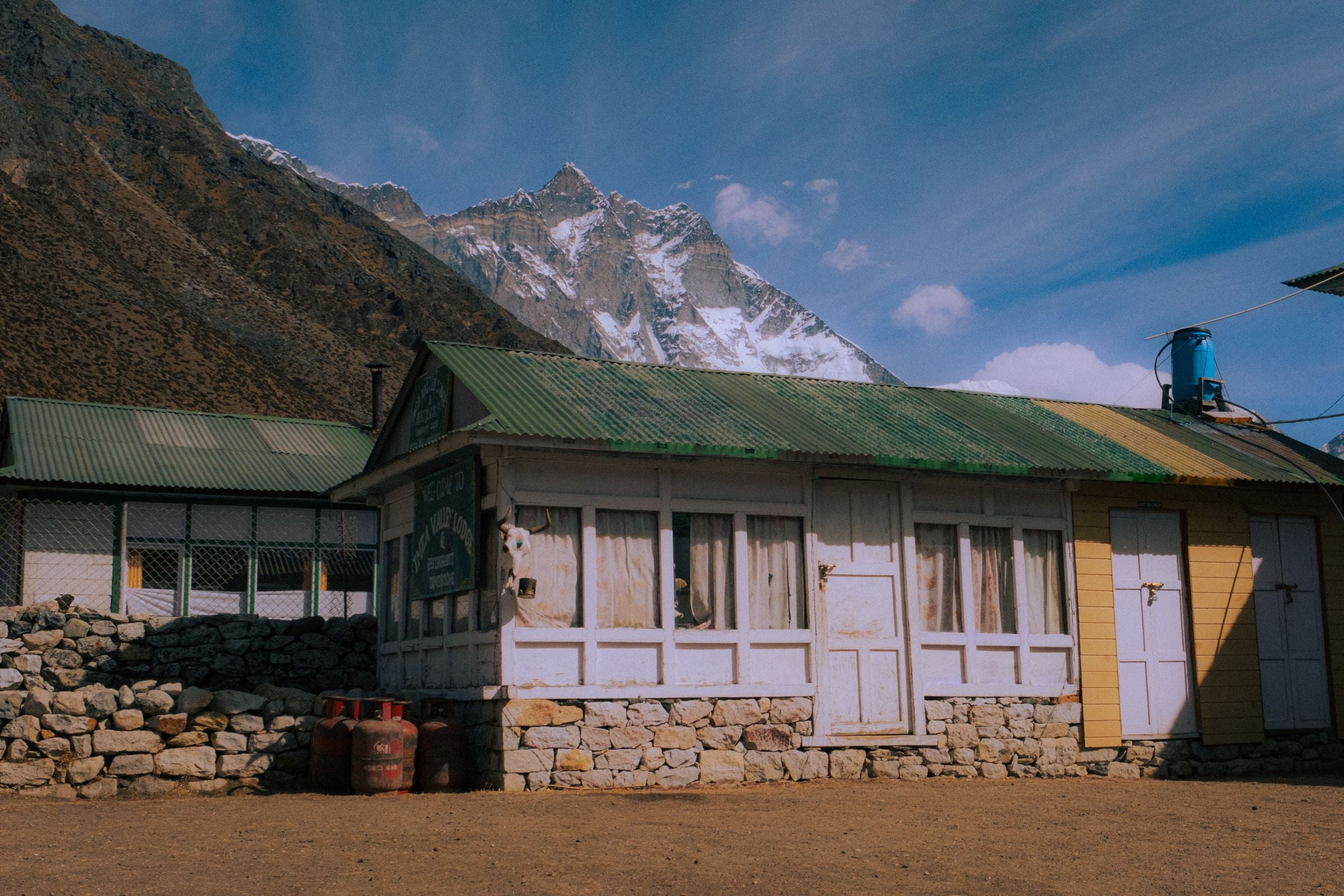 A painted teahouse on the Everest trail, snow faces standing behind its roofline