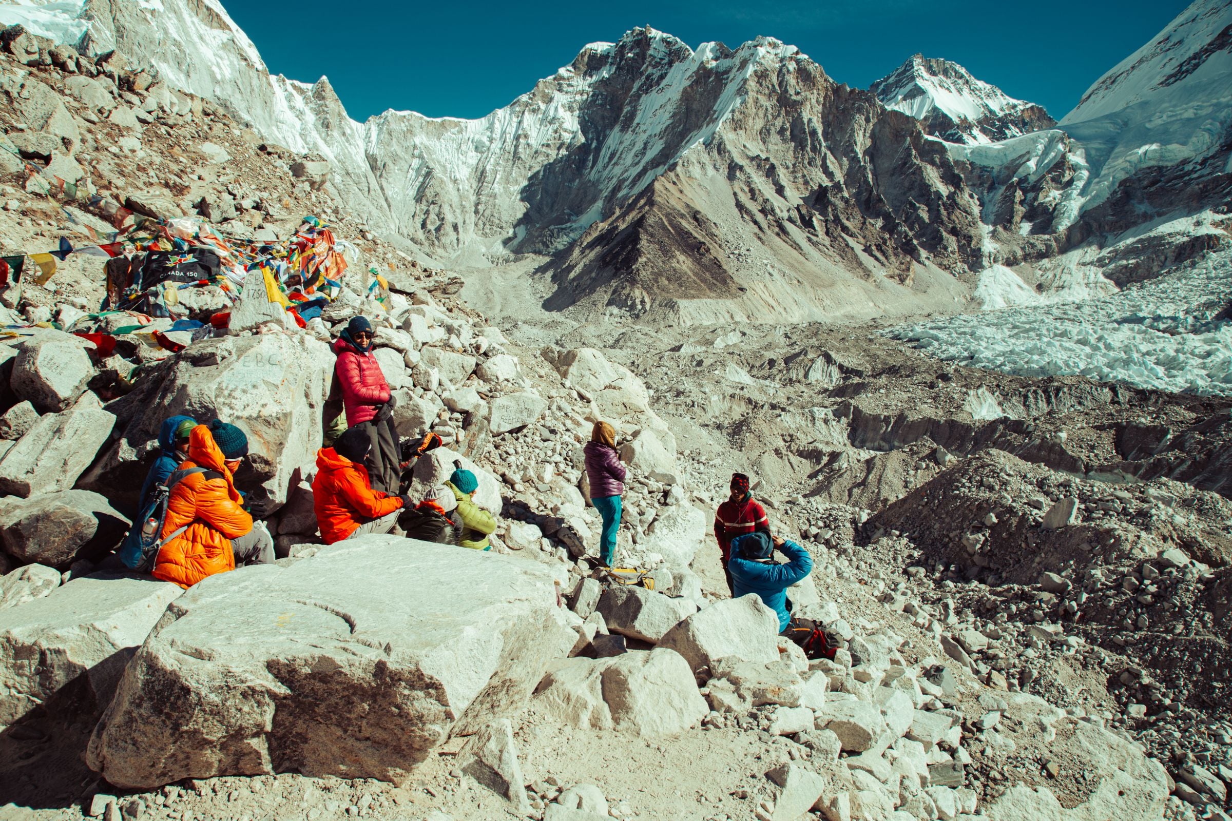 Trekkers resting among prayer flags on the moraine at Everest Base Camp