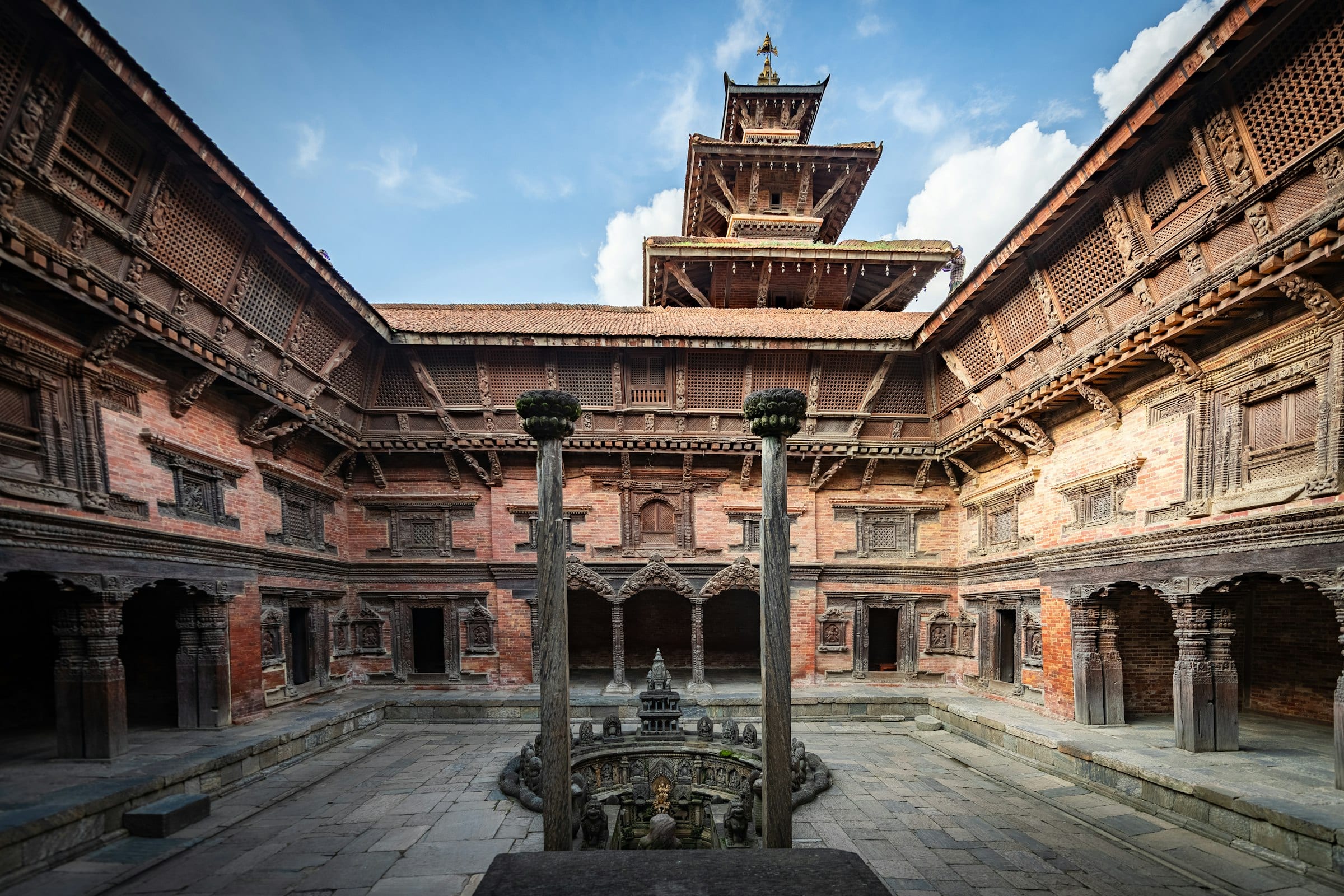 A carved palace courtyard with a sunken stone water spout in Patan